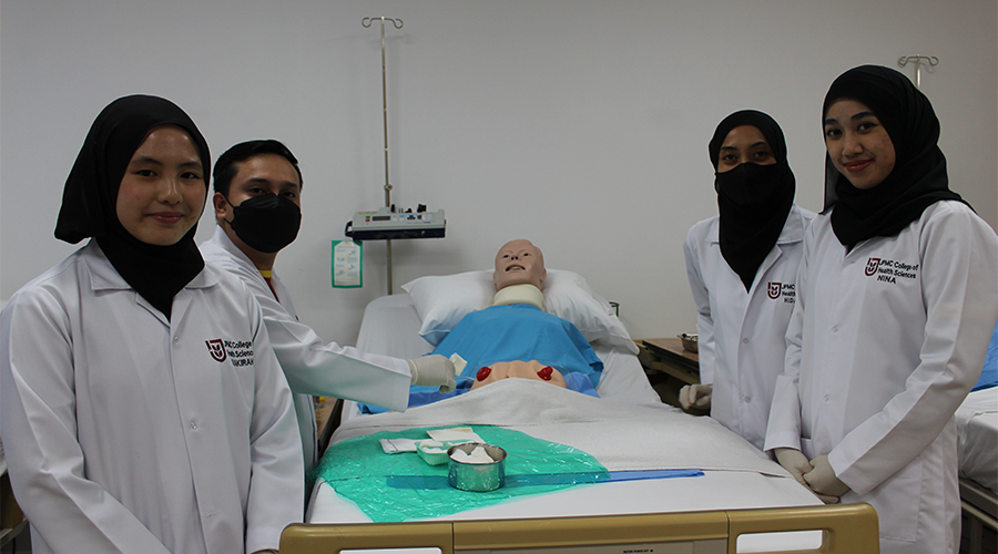 Nursing Course Brunei | A group of nursing students from JCHS engaged in clinical training with a nursing mannequin.