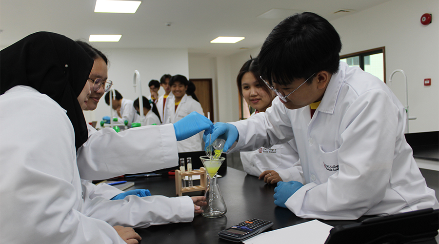 Nursing Course Brunei | A group of JCHS nursing students transferring chemicals from a beaker to a flask in a practical training session.
